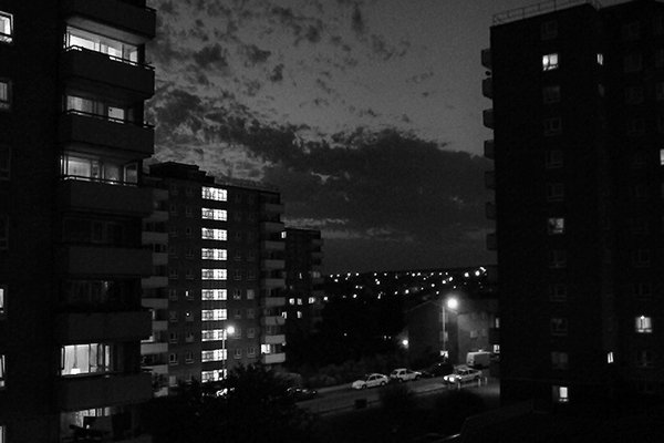 Lit windows in tower blocks at dusk with broken cloud above