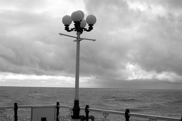 A lamp post on a pier deck under heavy cloud